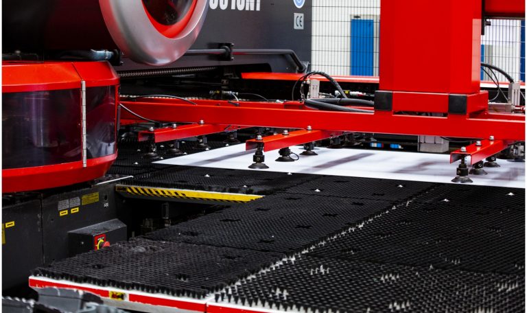 Close-up of a large industrial machine with red components in a manufacturing facility.