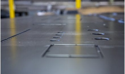 Close-up of a metal sheet with precision-cut holes, part of a manufacturing process.