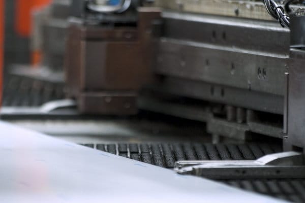 Close-up view of an industrial machine press with a metal sheet positioned for processing.